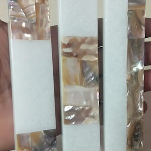 Può includere: Tre oggetti rettangolari in marmo bianco con intarsi decorativi di madreperla iridescente. Gli intarsi sono disposti in diversi motivi su ogni oggetto.