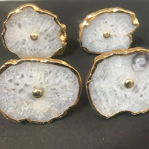 May include: Four white agate drawer pulls with gold trim. Each pull has a round knob in the center.