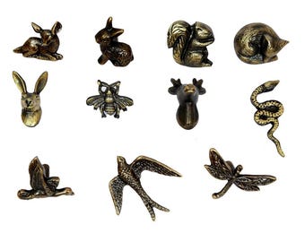 May include: A collection of bronze-toned animal figurines, including a rabbit, squirrel, hedgehog, bee, deer, snake, goose, swallow, and dragonfly. Each figurine is intricately detailed and designed with a vintage aesthetic.