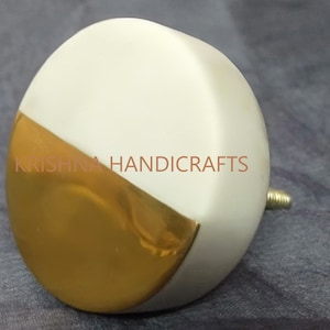 Peut inclure: Bouton de meuble blanc et doré avec une vis en laiton. Le bouton est de forme arrondie, avec une section dorée en diagonale. Le texte "KRISHNA HANDICRAFTS" est imprimé sur le bouton.