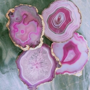 Peut inclure: Quatre sous-verres en agate rose avec une bordure dorée. Les sous-verres sont ronds et ont un aspect naturel et organique.