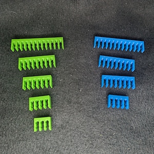 May include: A set of green and blue plastic cable organizers. The organizers are in different sizes and are arranged in a descending order from largest to smallest.