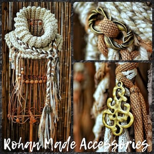 May include: A chunky knit cowl scarf in cream and brown tones featuring braided fabric strips, wooden beads, and antique brass-colored metal accents. The scarf includes a decorative metal clasp and a dangling filigree charm pendant.