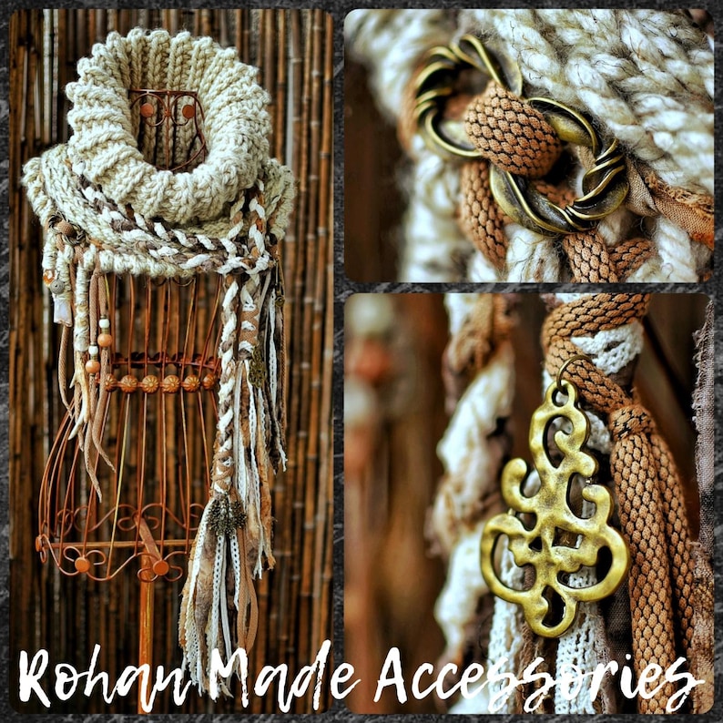 May include: A chunky knit cowl scarf in cream and brown tones featuring braided fabric strips, wooden beads, and antique brass-colored metal accents. The scarf includes a decorative metal clasp and a dangling filigree charm pendant.