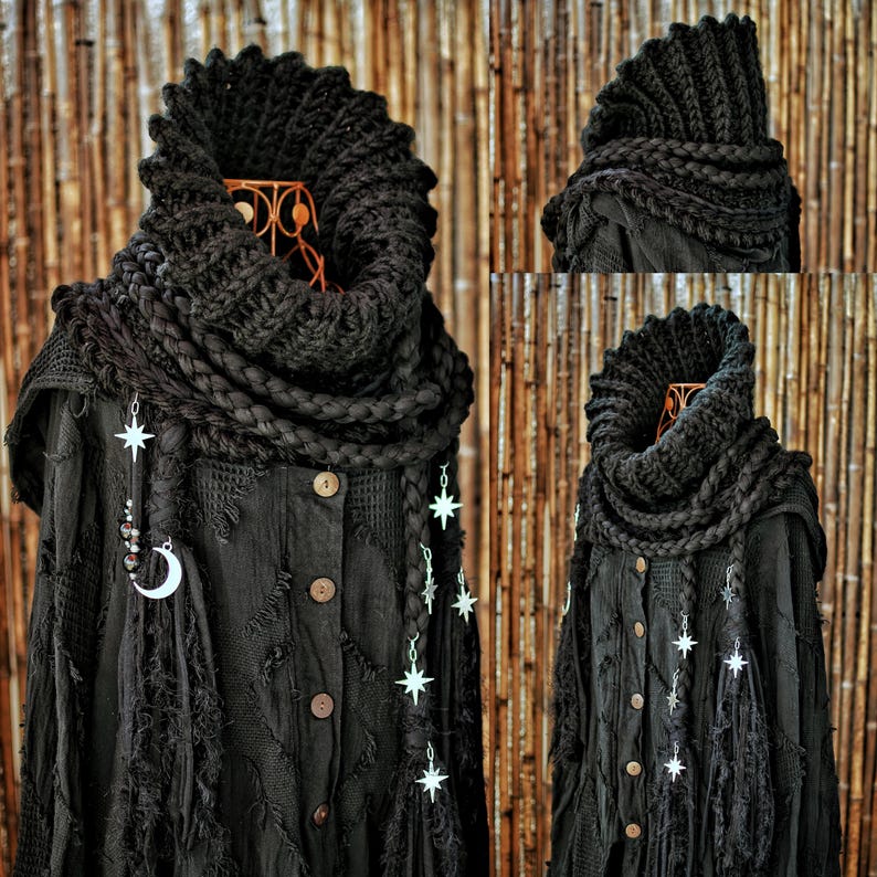May include: A black textured long-sleeve button-down shirt featuring a thick, chunky knit cowl neck scarf. The garment is adorned with dangling silver-toned star charms and a crescent moon charm, integrated into braided sections of the scarf.
