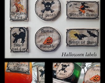 Puede incluir: Ocho etiquetas con temática de Halloween con diseños de punto de cruz. Las etiquetas están sobre un fondo blanco y presentan imágenes de un dragón, una calavera y huesos cruzados, una bruja, un gato negro, una calabaza y murciélagos. Las etiquetas están tituladas "Dragons Fire", "Potion of Death", "Witches Brew", "Black Cat Fur", "Rotten Pumpkin", y "Wings of Bats".