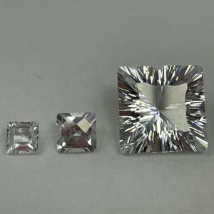 May include: Three clear quartz crystals cut into square shapes. The crystals are different sizes, with the largest being about 1 inch wide.