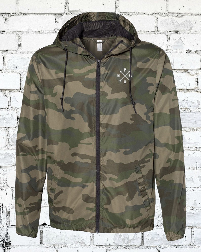 May include: A camouflage green hooded jacket with a black zipper and a white logo on the front that says "NPI" with a pine tree and arrows.