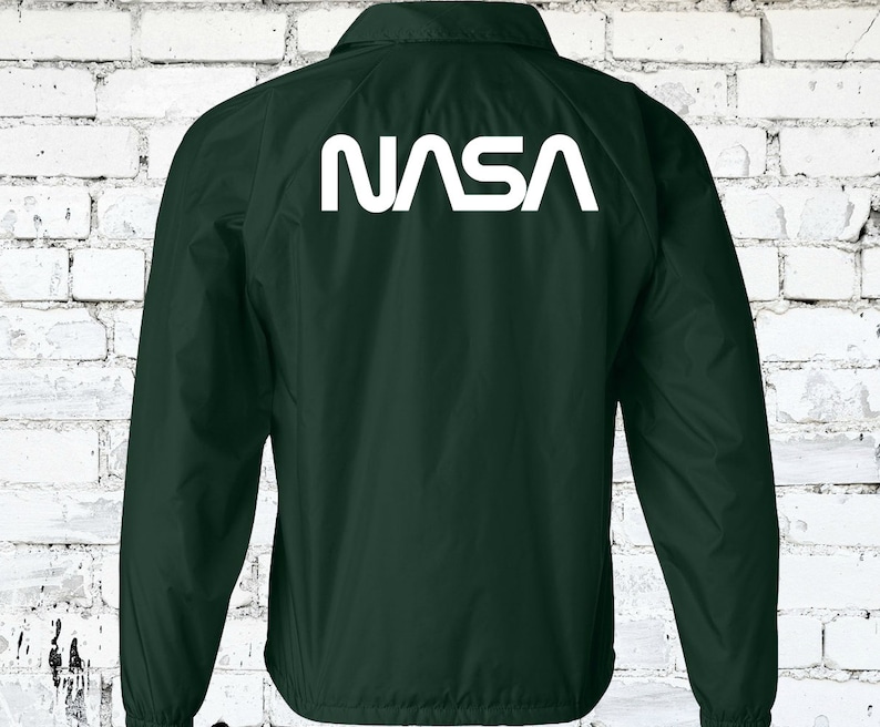 Puede incluir: Una chaqueta verde oscuro con un logotipo blanco de la NASA en la espalda.