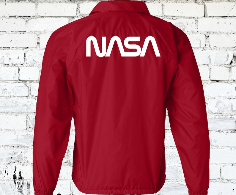 Puede incluir: Chaqueta cortavientos roja con un logotipo blanco de la NASA en la espalda.
