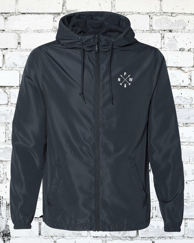 May include: A dark blue hooded jacket with a zipper closure and a white embroidered compass design on the chest. The compass design features the letters N, W, and P with a small tree in the center.