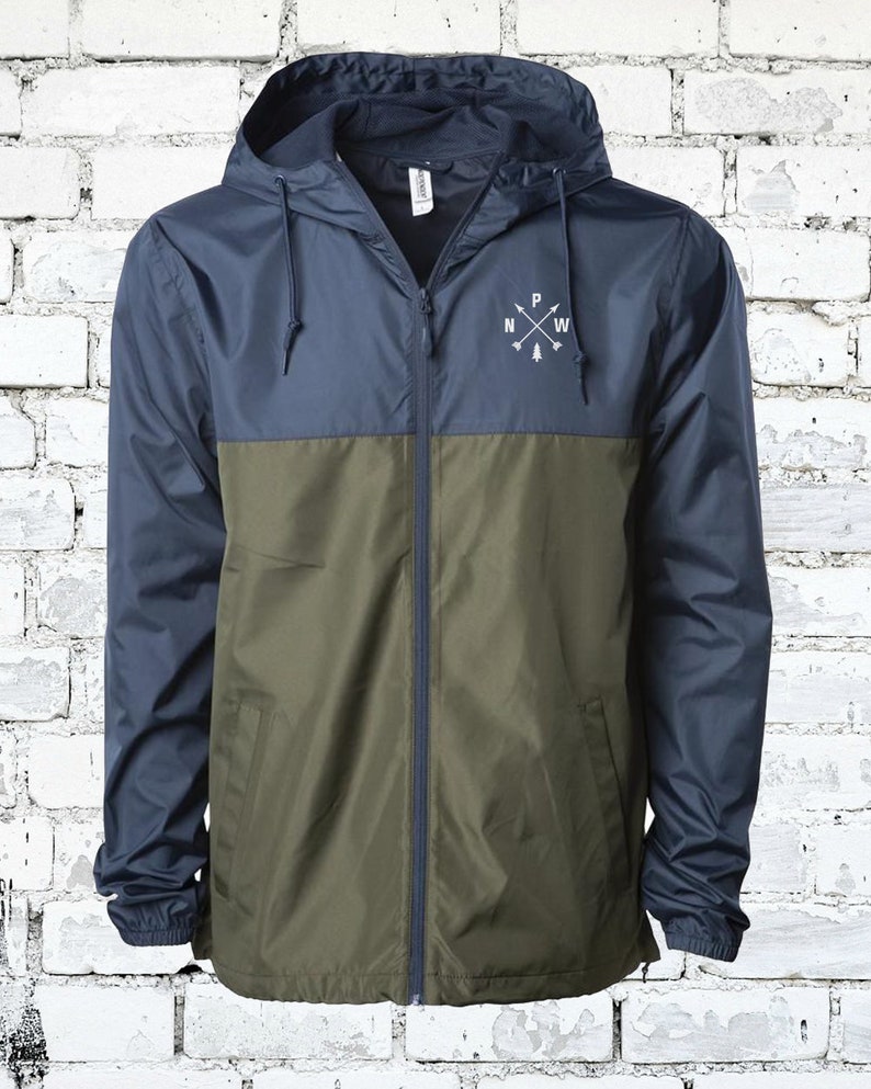 May include: A navy blue and olive green hooded jacket with a zipper closure. The jacket has a white logo on the chest that says "P NW" with arrows pointing north, west, east, and south.