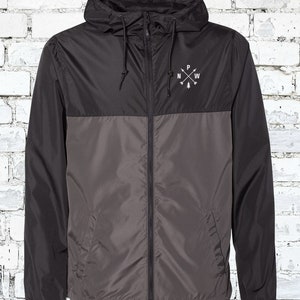 May include: A black and gray hooded jacket with a zipper closure. The jacket has a logo on the chest that says "N.W.P." with a small pine tree graphic.