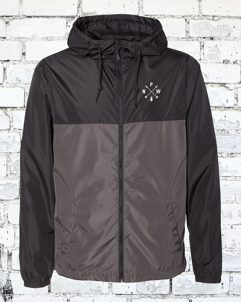 May include: A black and gray hooded jacket with a zipper closure. The jacket has a logo on the chest that says "N.W.P." with a small pine tree graphic.