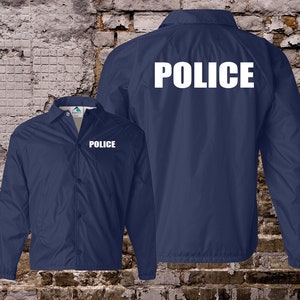 Peut inclure: Une veste bleu marine avec le mot "POLICE" imprim&eacute; en blanc sur le dos et l'avant. La veste a une fermeture &agrave; boutons et des manches longues.
