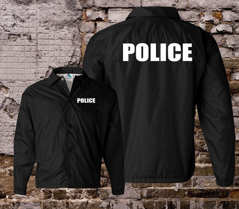 Peut inclure: Veste en nylon noire avec le mot "POLICE" imprim&eacute; en blanc &agrave; l'avant et &agrave; l'arri&egrave;re.