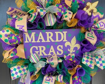 Puede incluir: Una corona de Mardi Gras con malla morada, verde y dorada, cintas y un letrero que dice "Mardi Gras".