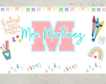 May include: A classroom banner with a pink "M" and the text "Mrs. Martinez" in blue. The banner also features a rainbow, crayons, and the alphabet and numbers. The banner is 96.5 cm by 61 cm.