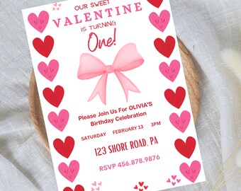 May include: A white invitation card with a pink bow and red hearts. The text on the card reads "Our Sweet Valentine is Turning One!" and includes details for a birthday celebration.