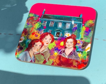 May include: A pink mug and coaster set featuring a colorful illustration of a house and figures. The mug has a black handle and rim. The coaster is square with rounded corners. The artwork has a vibrant, impressionistic style.
