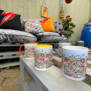 May include: Four ceramic mugs with colorful illustrations of a city skyline. The mugs are arranged on a wooden surface. The mugs are in different colors: orange, yellow, white, and blue.