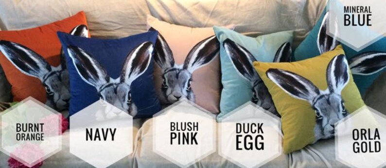 May include: Ten decorative throw pillows with a hare design in various colors, including burnt orange, navy, blush pink, duck egg, and orla gold. The pillows are arranged on a couch with a white background. The text "Mineral Blue" is visible in the top right corner of the image.