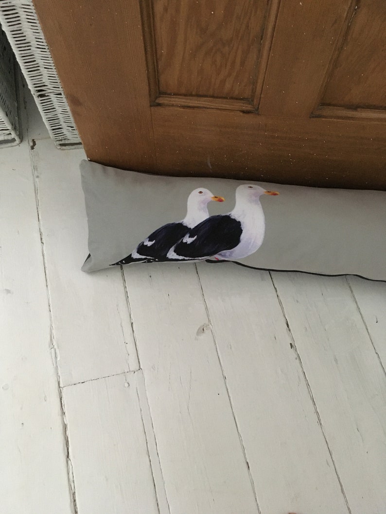 May include: A gray doorstop with a printed image of two seagulls. The seagulls are facing right and have black and white markings.