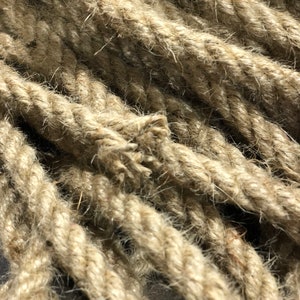 May include: Close-up of thick, natural-colored rope. The rope is tightly twisted, with visible fibers and a slightly frayed end. The texture appears rough and durable, suggesting a nautical or rustic theme.