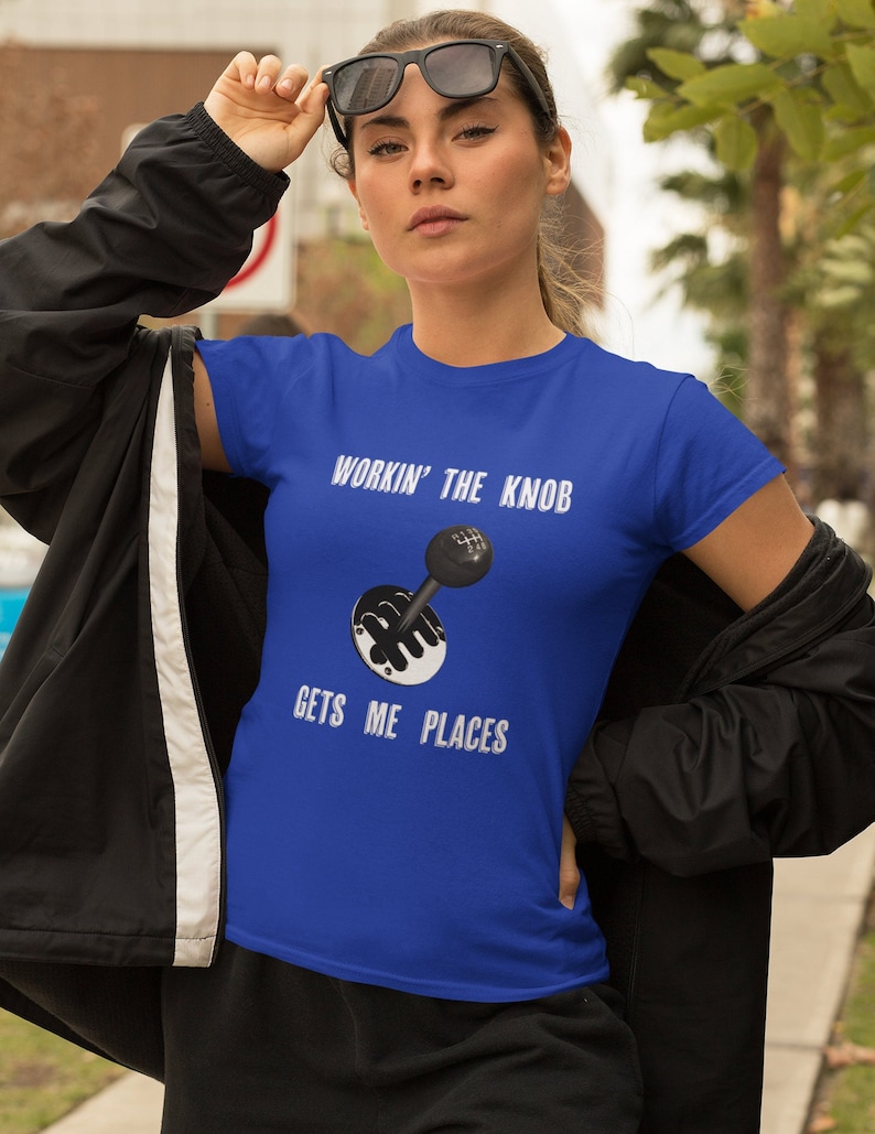 May include: A royal blue t-shirt with a white graphic of a car's gear shifter and the text "Workin' the Knob Gets Me Places".