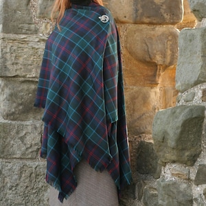 May include: A blue, green and red tartan shawl with fringed edges. The shawl is draped over a person's shoulders and secured with a silver brooch.