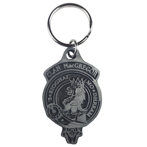 May include: A silver-colored Clan MacGregor keychain. The keychain features a shield-shaped pendant with the words "Clan MacGregor" and "'S Rioghal Mo Dhream" encircling a lion rampant. A metal ring is attached.
