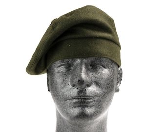 Op de afbeelding: Een donkergroene wollen baret met een gevouwen rand. De baret wordt gedragen op een grijs mannequinhoofd.
