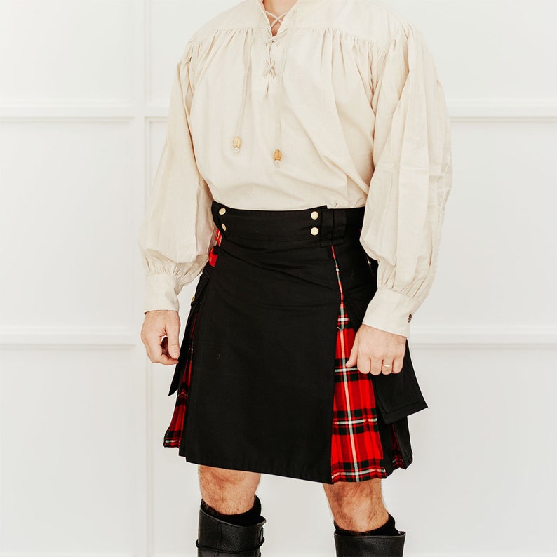 May include: A black kilt with a red and black tartan panel on the right side. The kilt has a gold buckle and is worn with a white button-down shirt.