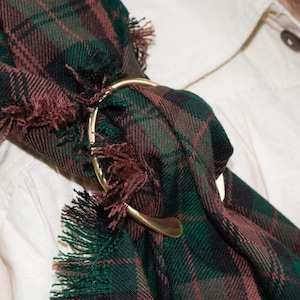 May include: A green, black, and brown plaid kilt with a gold metal kilt pin.