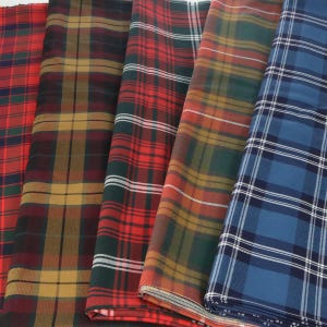 Pode incluir: Quatro tecidos xadrez diferentes em várias cores, incluindo vermelho, verde, azul e dourado. Os tecidos são dobrados e empilhados uns sobre os outros.