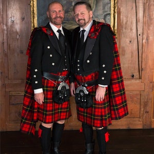 Puede incluir: Dos personas con kilt escoc&eacute;s tradicional, chaquetas negras y corbatas de lazo negras a juego. Los kilts son de cuadros rojos, negros y amarillos.