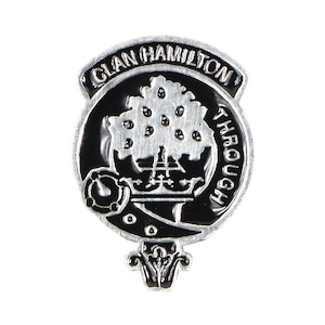 Może przedstawiać: Srebrna i czarna odznaka herbu klanowego z napisem "Clan Hamilton Through" wokół krawędzi. Herb przedstawia drzewo z koroną i mieczem.