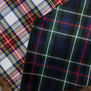 May include: Two pieces of fabric with plaid patterns. One fabric is white with red, blue, and yellow plaid. The other fabric is dark blue with green, white, and red plaid.