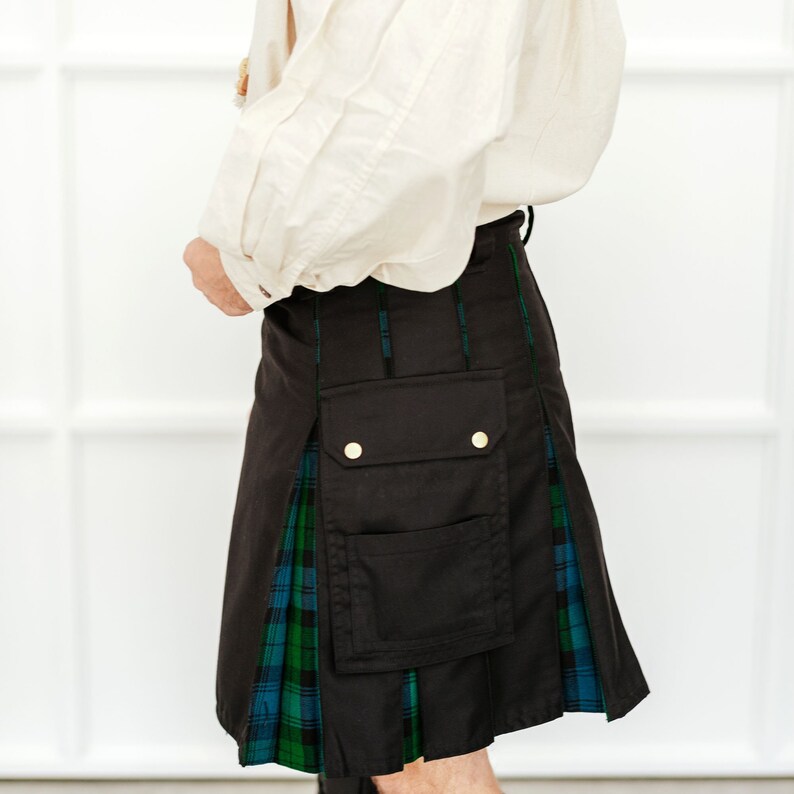 May include: A black kilt with a green and blue tartan pattern. The kilt has a large cargo pocket on the front and two gold buttons.
