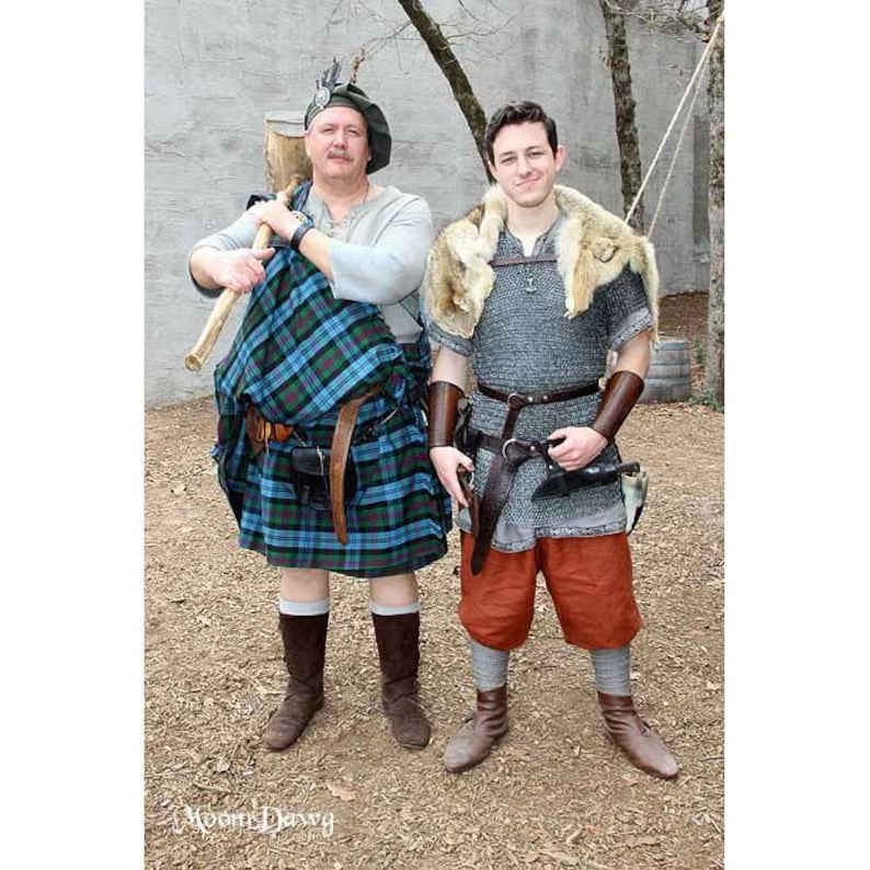 May include: Two people dressed in medieval garb. One person is wearing a kilt and holding a wooden club. The other person is wearing chainmail and a fur-lined tunic.
