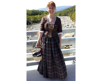 May include: A woman wearing a brown and plaid dress with a lace-up bodice and a basket in her hand. She is standing on a bridge over a river.