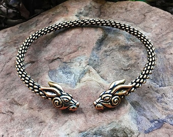 May include: A gold-toned metal necklace with two wolf head ends. The necklace is made of a chain-like design.