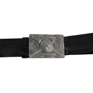 May include: A black leather belt with a silver buckle featuring a Celtic knot design with a shield and crossed swords.
