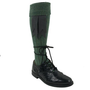 May include: Green and black knee-high socks with a decorative black tassel. The socks are worn with black leather shoes.