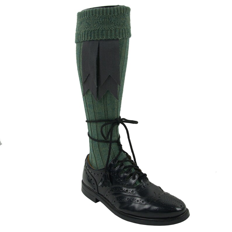 May include: Green and black knee-high socks with a decorative black tassel. The socks are worn with black leather shoes.