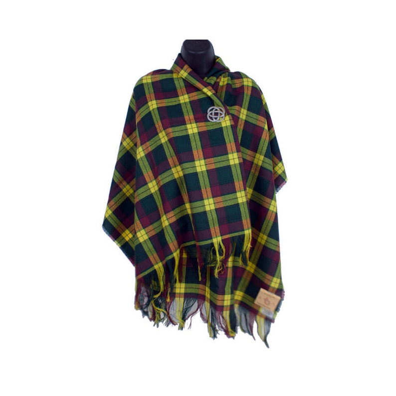 Puede incluir: Un poncho a cuadros en tonos verdes, amarillos y burdeos, exhibido en un maniqu&iacute;. El poncho presenta un dobladillo con flecos y un broche plateado. La tela tiene un patr&oacute;n de tart&aacute;n cl&aacute;sico.