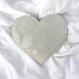 Cartera grande en forma de corazón de piel de serpiente sintética blanca con interior iridiscente y compartimentos.