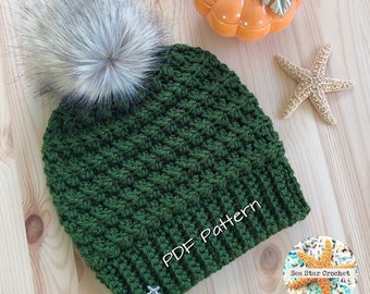 May include: A green crocheted beanie with a faux fur pom pom. The beanie has the text "PDF Pattern" embroidered on the side.