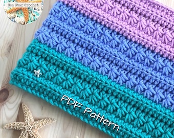 May include: A crochet pattern for a colourful scarf with a starburst stitch. The scarf is made in shades of teal, blue, and purple. The text "PDF Pattern" is visible in the image.