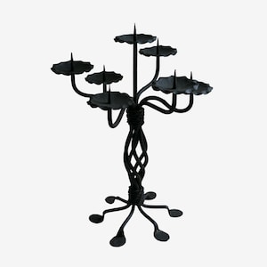 May include: Black wrought iron candelabra with five candle holders and a twisted base. The candelabra has a traditional design and is perfect for adding a touch of elegance to any home.